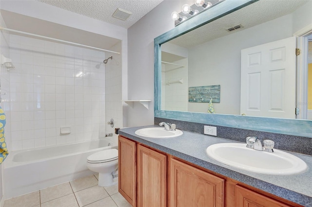 full bathroom with toilet, vanity with extensive cabinet space, tiled shower / bath, tile flooring, and double sink