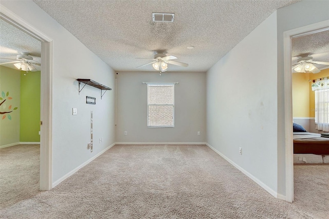 unfurnished room featuring a healthy amount of sunlight, ceiling fan, and light colored carpet