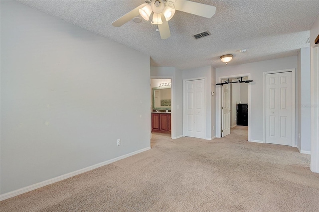 unfurnished room with light colored carpet, ceiling fan, and a textured ceiling