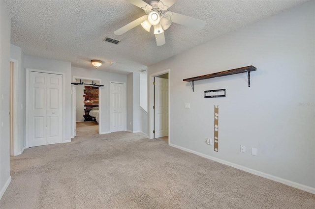 interior space with a barn door, ceiling fan, and a textured ceiling