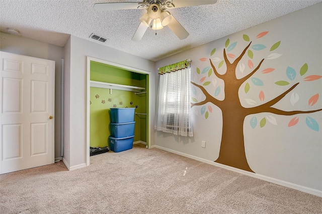 unfurnished bedroom with a closet, ceiling fan, carpet, and a textured ceiling