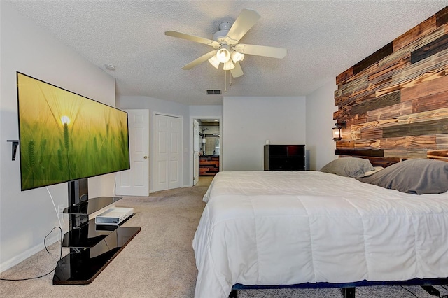 carpeted bedroom featuring wood walls, ceiling fan, and a textured ceiling