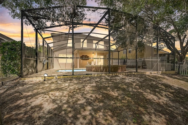 back house at dusk featuring a fenced in pool and a lanai