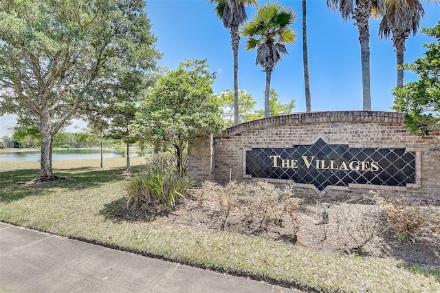 community / neighborhood sign with a water view and a lawn