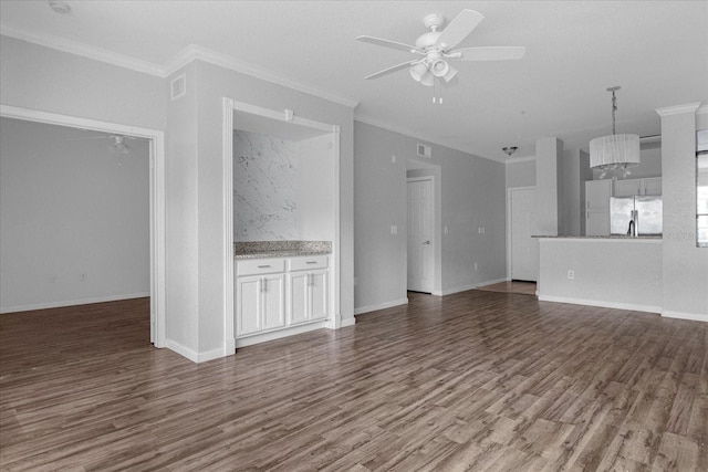 unfurnished living room featuring dark hardwood / wood-style floors, ceiling fan with notable chandelier, and ornamental molding