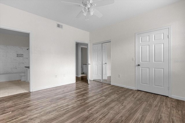 unfurnished bedroom with ensuite bath, ceiling fan, and hardwood / wood-style flooring