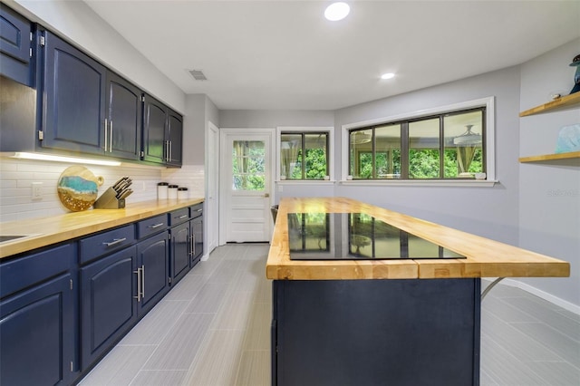 kitchen featuring blue cabinetry, black electric stovetop, backsplash, and butcher block countertops