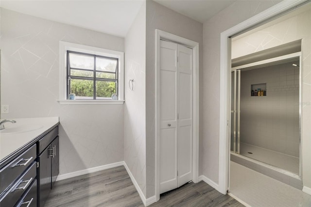 bathroom featuring hardwood / wood-style floors, vanity, and a tile shower