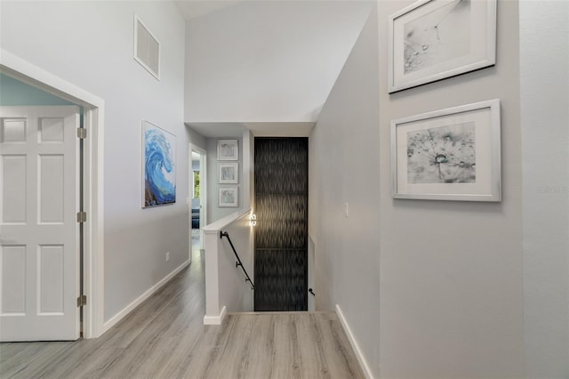 hallway featuring a towering ceiling and light hardwood / wood-style flooring