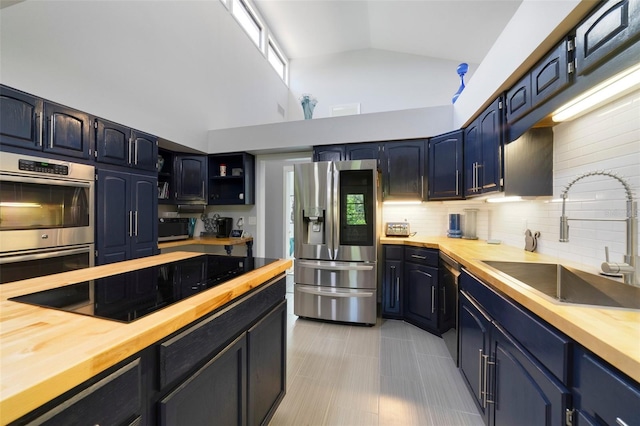 kitchen with wood counters, blue cabinets, sink, black appliances, and high vaulted ceiling