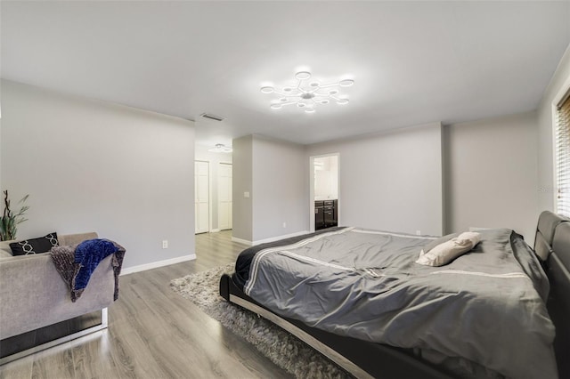 bedroom with ensuite bath and light hardwood / wood-style flooring