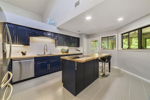 kitchen featuring wood counters, a breakfast bar, blue cabinets, sink, and stainless steel appliances