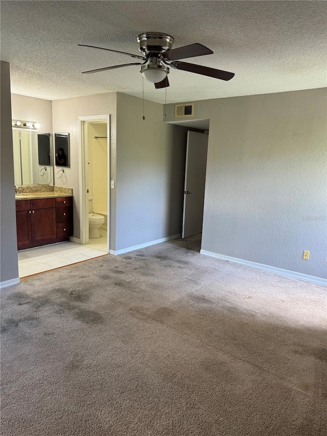 unfurnished bedroom with light colored carpet, visible vents, a textured ceiling, and ensuite bathroom