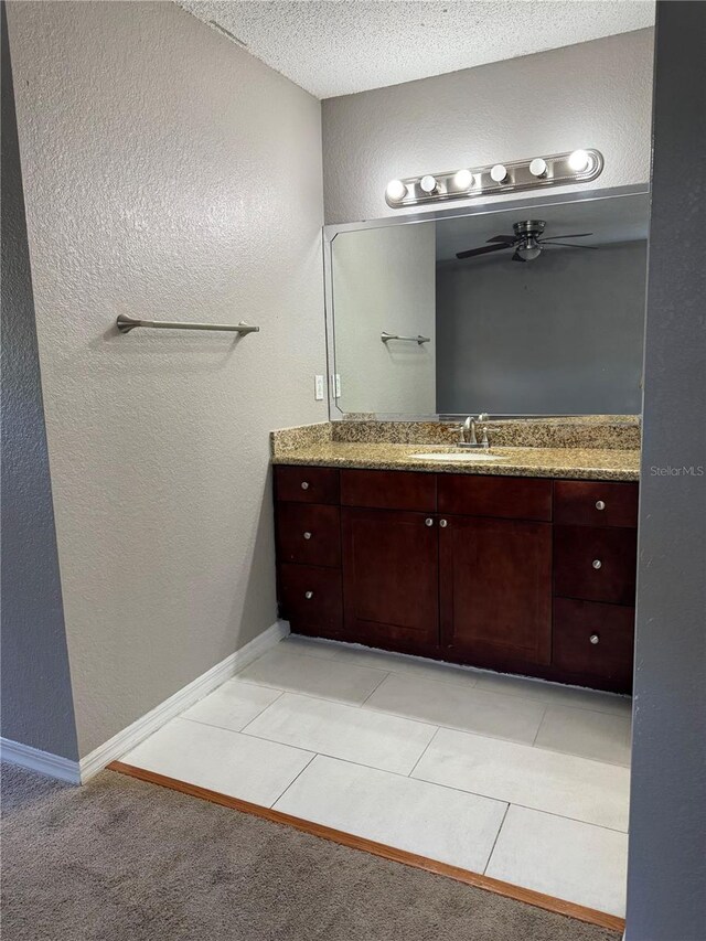 bathroom featuring a textured wall, ceiling fan, vanity, a textured ceiling, and baseboards