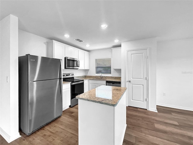 kitchen with a center island, stainless steel appliances, white cabinetry, and hardwood / wood-style floors