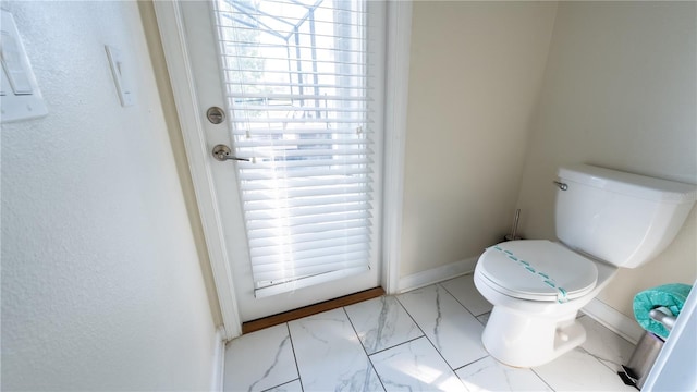 bathroom featuring a wealth of natural light, toilet, and tile floors