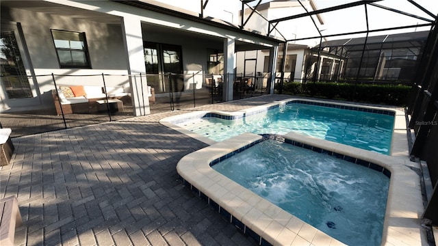 view of swimming pool featuring a lanai, an in ground hot tub, and a patio area