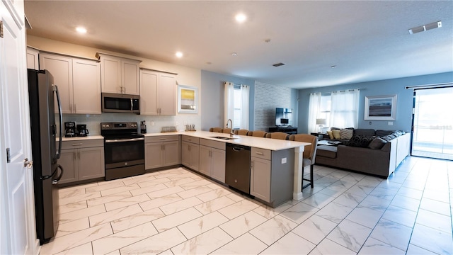 kitchen with appliances with stainless steel finishes, gray cabinets, kitchen peninsula, backsplash, and sink