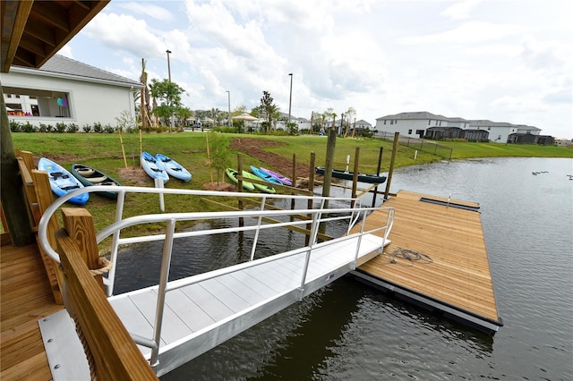 view of dock with a yard and a water view