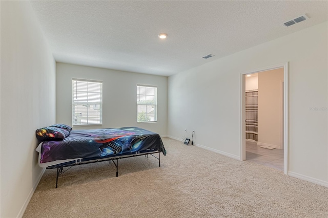 bedroom featuring carpet flooring, connected bathroom, and a textured ceiling