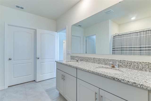 bathroom featuring tile flooring, dual sinks, and vanity with extensive cabinet space