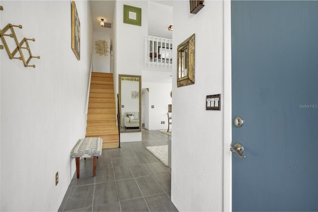 hallway featuring a high ceiling and dark tile floors