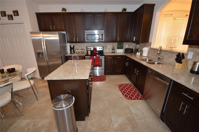 kitchen featuring a kitchen island, stainless steel appliances, backsplash, and light stone counters