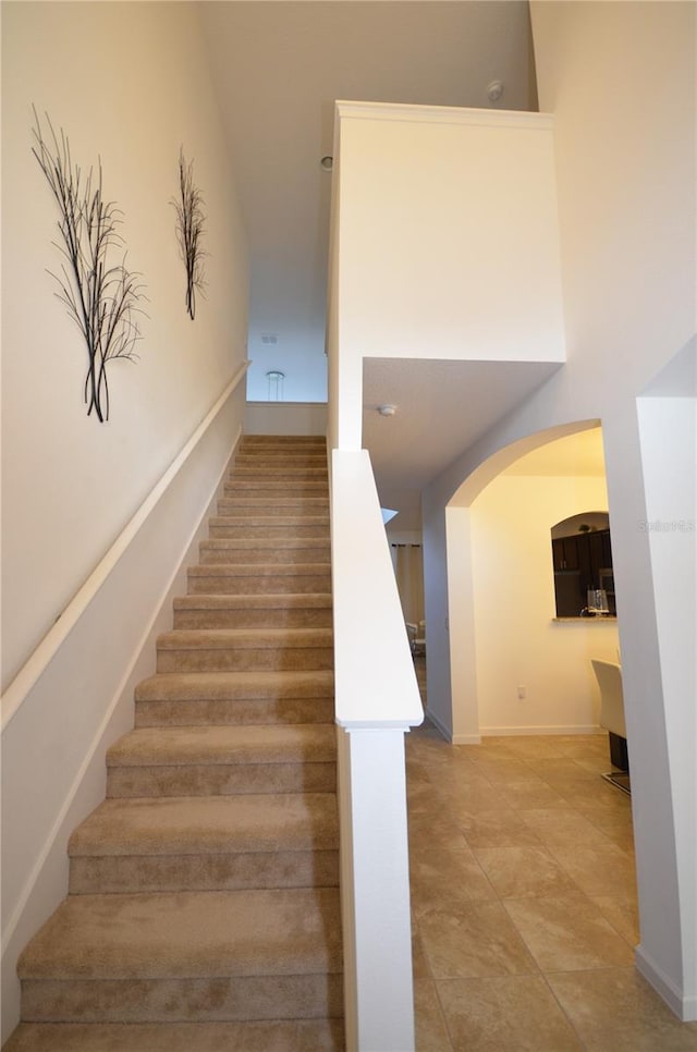 staircase with tile floors and a high ceiling