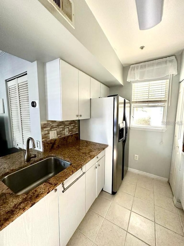 kitchen featuring light tile patterned flooring, white cabinetry, sink, and backsplash