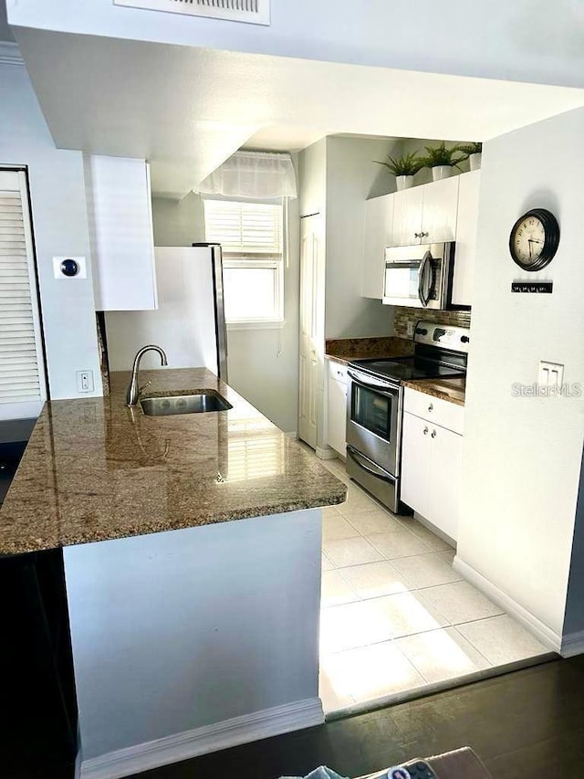 kitchen with white cabinets, kitchen peninsula, appliances with stainless steel finishes, and sink