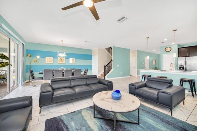 tiled living room featuring ceiling fan with notable chandelier