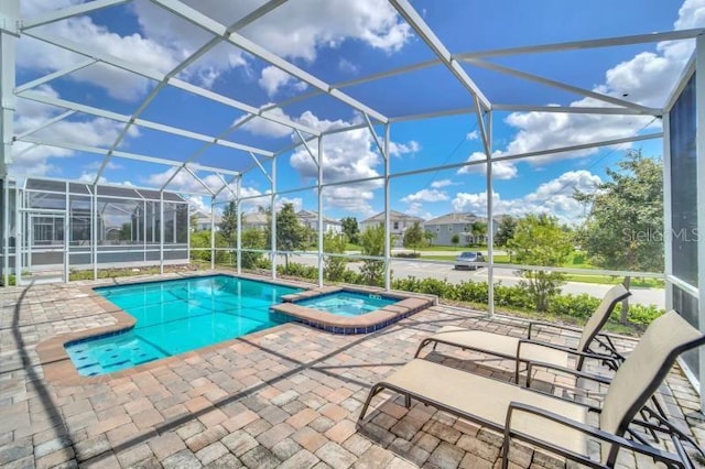 view of swimming pool featuring a patio area, an in ground hot tub, and glass enclosure