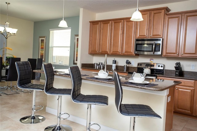 kitchen with appliances with stainless steel finishes, a center island, a breakfast bar, light tile flooring, and decorative light fixtures