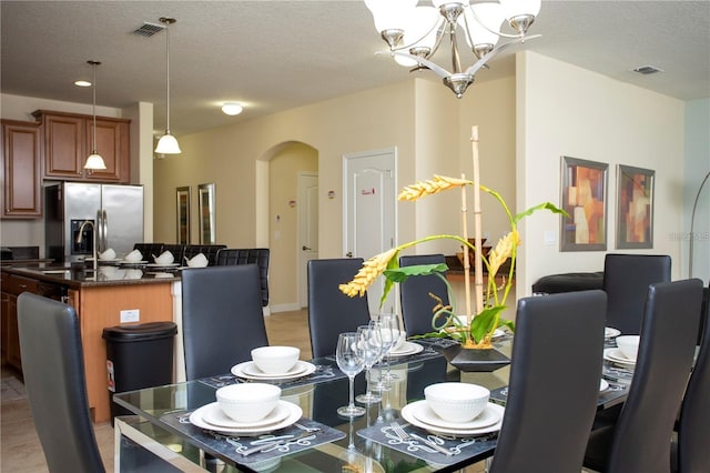 dining space featuring a notable chandelier, light tile floors, and a textured ceiling