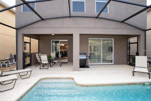 view of swimming pool with a patio, glass enclosure, and grilling area