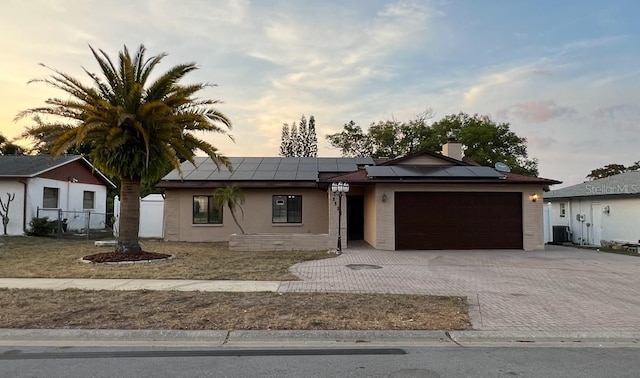 ranch-style home featuring a garage, central AC, and solar panels