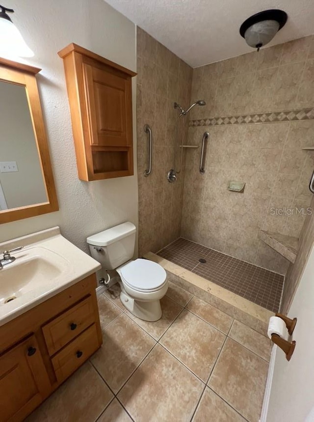 bathroom with tile flooring, a textured ceiling, a tile shower, vanity, and toilet