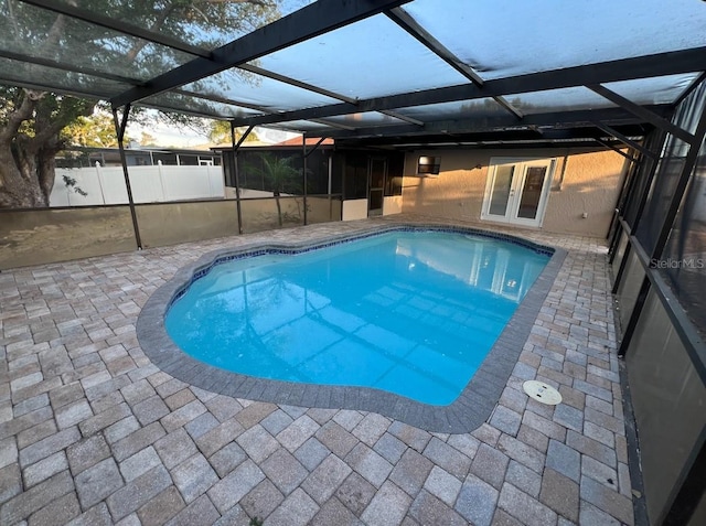 pool at dusk featuring a patio and a lanai