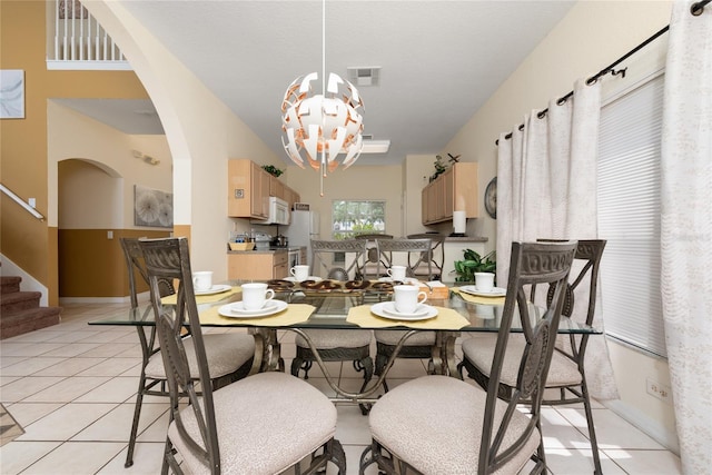 tiled dining room with an inviting chandelier