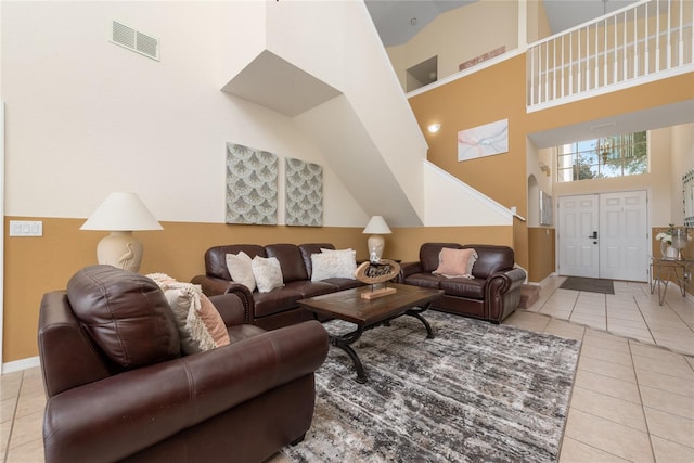 living room with a towering ceiling and tile flooring