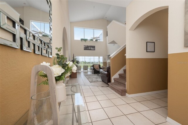 entrance foyer with high vaulted ceiling and light tile floors