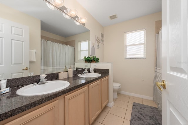 bathroom with a wealth of natural light, double sink, toilet, and vanity with extensive cabinet space