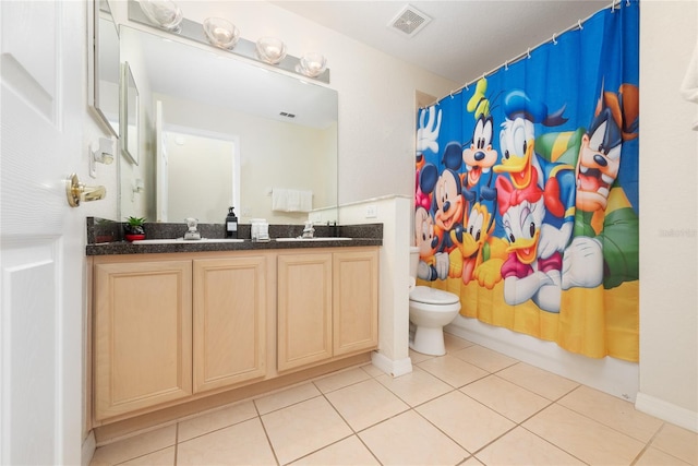 bathroom featuring tile flooring, toilet, and double sink vanity