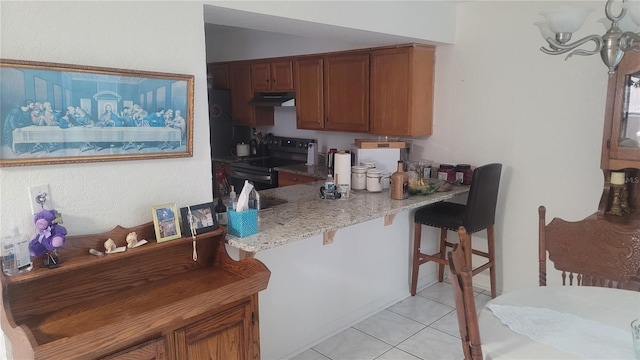 kitchen with kitchen peninsula, stainless steel electric range, light tile patterned floors, a kitchen breakfast bar, and light stone countertops