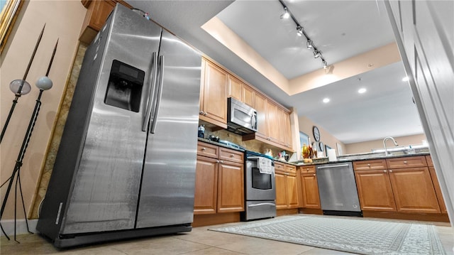 kitchen with appliances with stainless steel finishes, dark stone countertops, sink, backsplash, and light tile patterned flooring