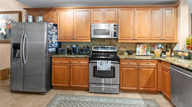 kitchen featuring tasteful backsplash, light tile patterned floors, light stone counters, and stainless steel appliances