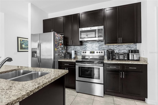 kitchen with light stone countertops, sink, stainless steel appliances, decorative backsplash, and light tile patterned flooring