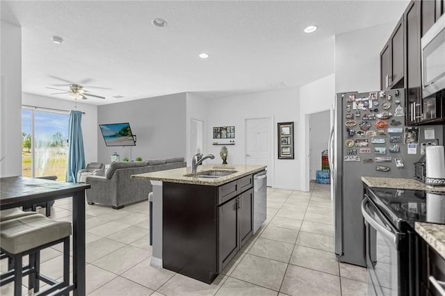 kitchen featuring a kitchen island with sink, sink, ceiling fan, light tile patterned floors, and appliances with stainless steel finishes