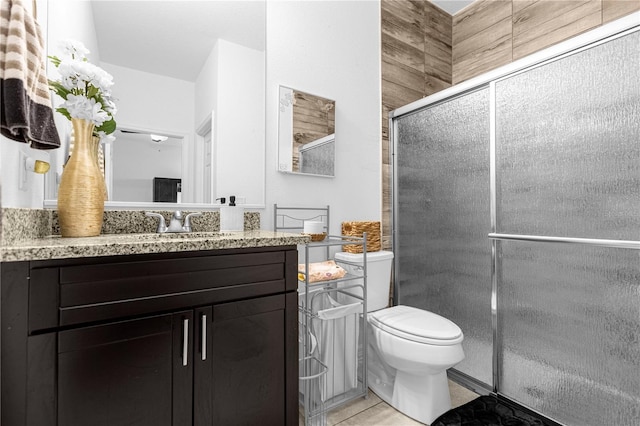 bathroom with tile patterned flooring, vanity, an enclosed shower, and toilet