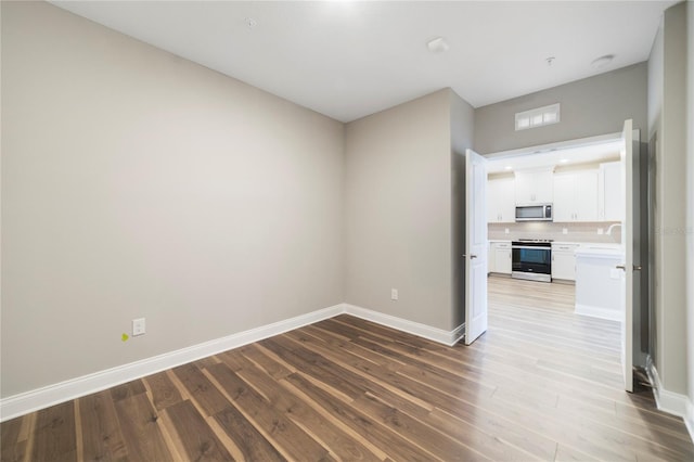 unfurnished room featuring wood-type flooring and sink